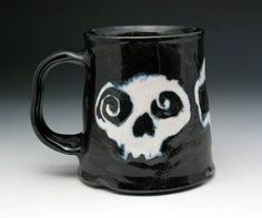 a black and white coffee mug with a skull painted on it