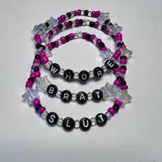 two black and pink beads with silver letters on each bead are attached to bracelets