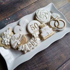 a white plate topped with cookies covered in icing next to wedding rings and engagement rings