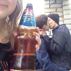 a woman holding up a bottle of beer