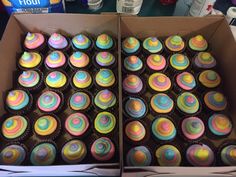 two boxes filled with colorful cupcakes on top of a table