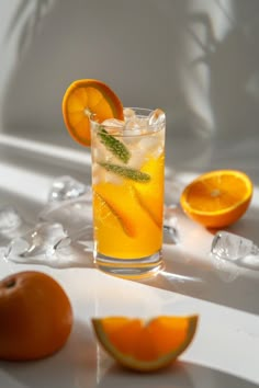 an orange drink with ice and garnish on the rim, surrounded by sliced oranges