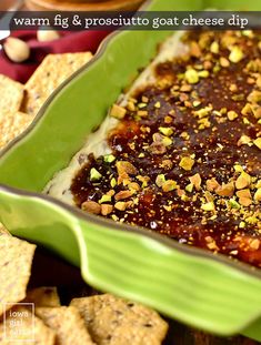 a green casserole dish filled with hummus and garnished with nuts