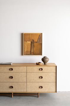 a wooden dresser sitting next to a painting on the wall