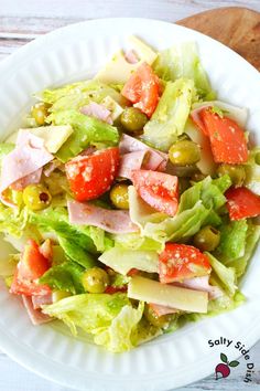 a white plate topped with salad on top of a wooden table