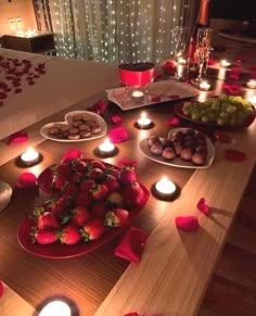 a table topped with plates of fruit and candles