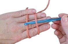 two hands holding an orange string and a blue crochet hook with one hand