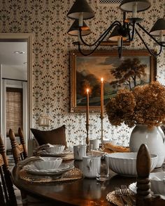 a dining room table with plates, cups and saucers in front of a painting on the wall