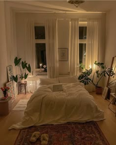 an unmade bed sitting in a bedroom next to two windows with plants on them