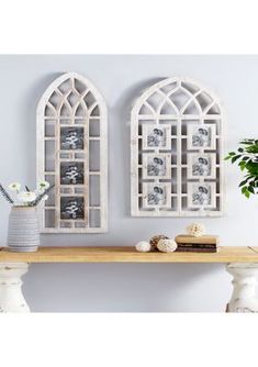 two white wall hangings with pictures on them next to a vase and bookshelf