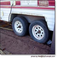 the trailer has two tires attached to it's flatbed and is parked on dirt