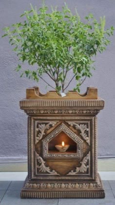 a potted plant sitting on top of a wooden stand with a lit candle in it