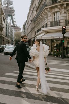 a bride and groom crossing the street in paris