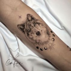 a tattoo on the arm of a person with a wolf head and moon phases around it