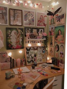 a desk with many pictures on the wall and lights above it, along with candles