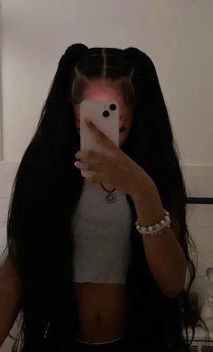 a woman taking a selfie with her cell phone in the bathroom while wearing long black hair