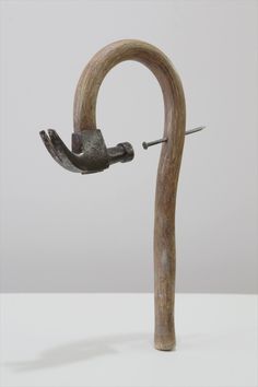 a sculpture made out of wood and metal with a hook in the middle that is holding an object