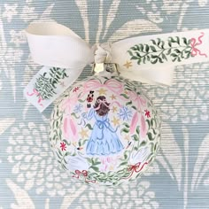 a decorated christmas ornament with a white ribbon on the top and an image of a woman wearing a blue dress