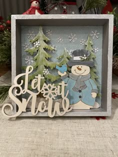 a christmas card with a snowman and pine trees in the background that says let it snow