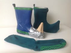 two pairs of green and blue rain boots next to each other on a white surface