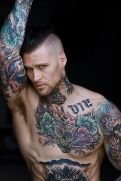 a man with lots of tattoos on his chest and arm is posing for the camera