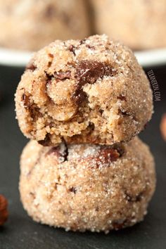 two chocolate chip cookies stacked on top of each other next to a bowl of nuts