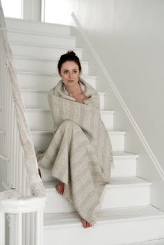 a woman wrapped in a blanket sitting on the stairs