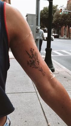 a person with a flower tattoo on their arm walking down the street next to a traffic light