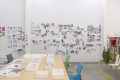 an office with several desks and chairs in front of a whiteboard that has pictures on it