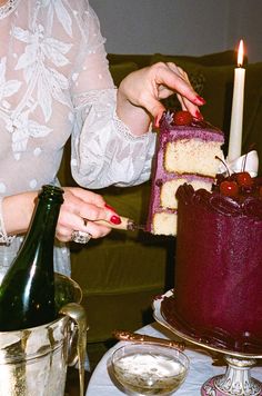 a woman is decorating a cake on a table with wine and ice buckets