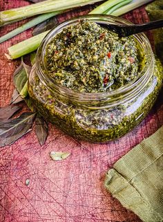 a jar filled with pesto next to some green vegetables