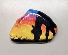 a painted rock with a silhouette of a giraffe