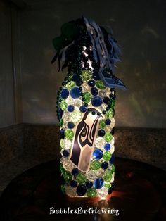 a lighted bottle is decorated with blue, green and white balls