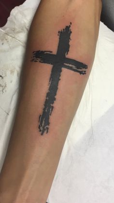 a person with a cross tattoo on their arm