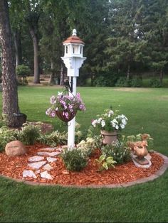 a garden with flowers and plants in the middle of it, surrounded by rocks and grass