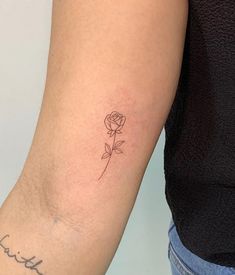 a woman's arm with a single rose tattoo on the left side of her arm