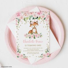 a pink and gold baby shower with a fox on it's back, surrounded by flowers