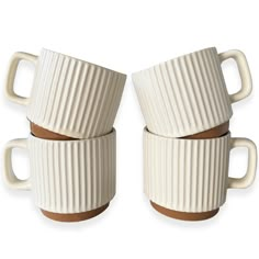 three white coffee cups stacked on top of each other with brown rims and handles