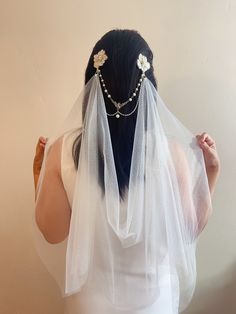 the back of a woman wearing a veil with flowers and pearls on it's head