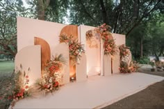 an outdoor ceremony setup with flowers and greenery on the wall, surrounded by candles