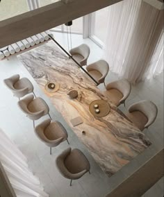 an aerial view of a dining room table with chairs and a large marble slab in the center