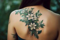 the back of a woman's shoulder with white flowers on it and green leaves