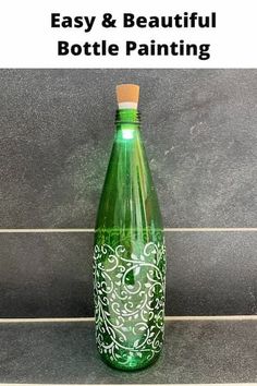 a green bottle sitting on top of a tile floor next to a wall with the words easy and beautiful bottle painting