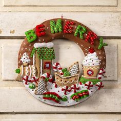 a decorated christmas wreath hanging on the side of a building with gingerbread houses and candy canes