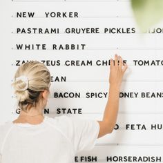 a woman writing on a wall with white letters