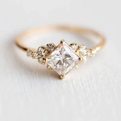 a gold ring with a princess cut diamond surrounded by small diamonds