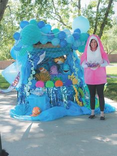 a woman standing in front of a blue tent with fish and bubbles on the top