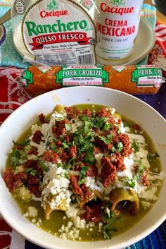 a white bowl filled with food next to yogurt and ranchero sauces