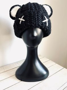 a black knitted hat with white ears on top of a mannequin head