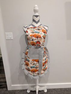 an apron is on display in front of a white mannequin and gray wall